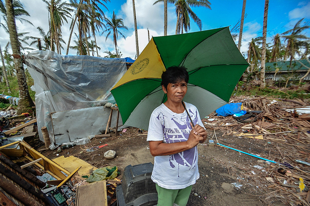 victim of an environmental disaster holding an umbrella amid debris